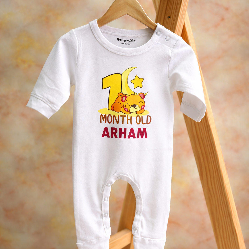 Baby onesie with '1 Month Old Arham' text and cartoon design on a wooden hanger.