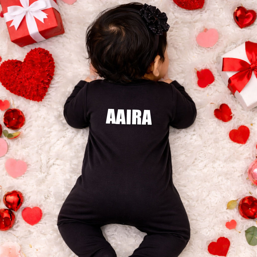 Baby in a black onesie with 'AIRA' on it, surrounded by red and pink hearts and gift boxes.