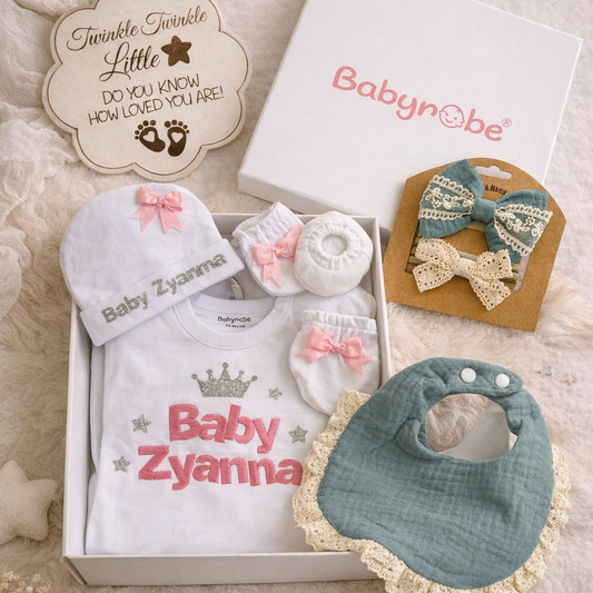 Baby gift set with personalized items and 'Babyn'be' packaging on a textured surface.