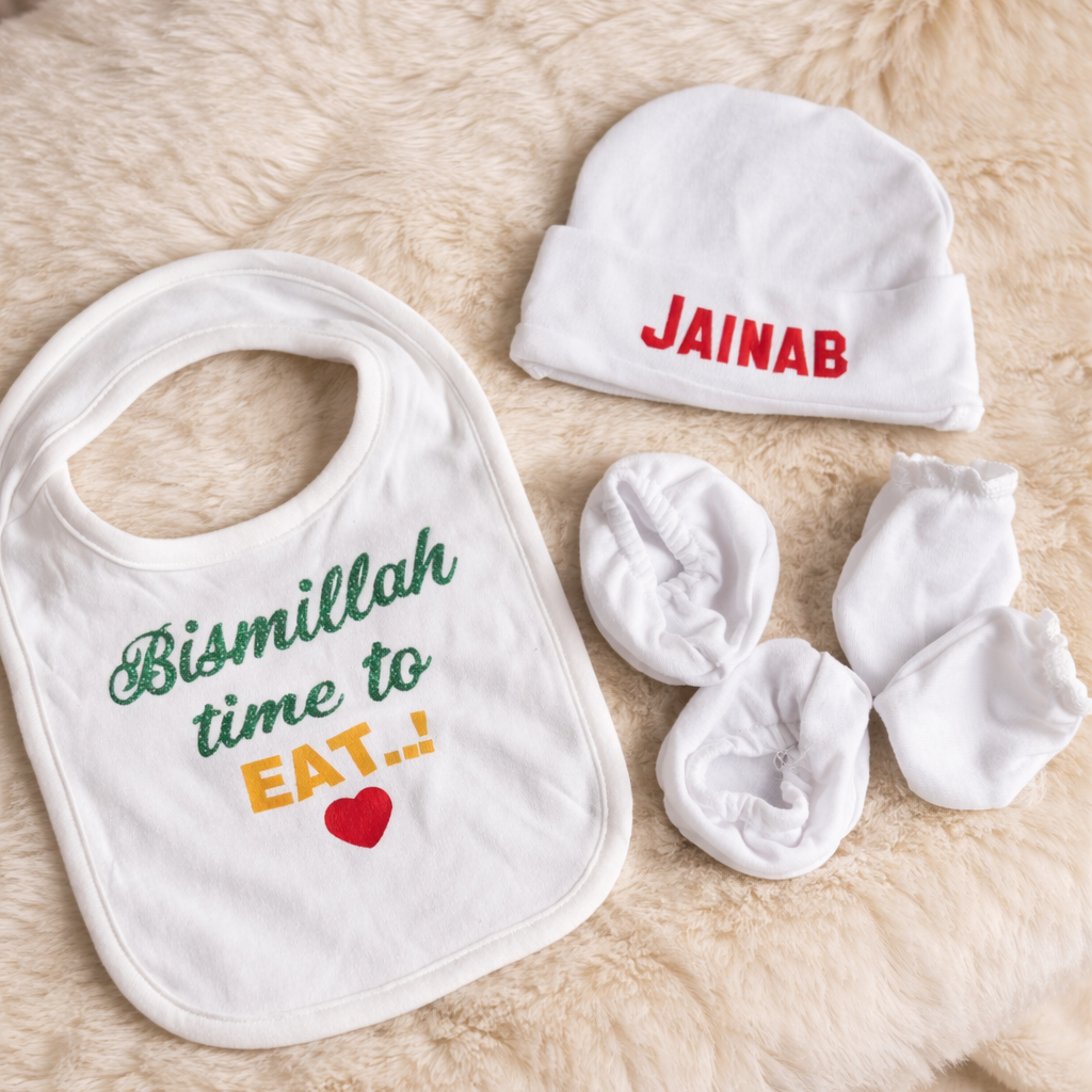 Baby bib, hat, and booties with personalized name on a soft surface