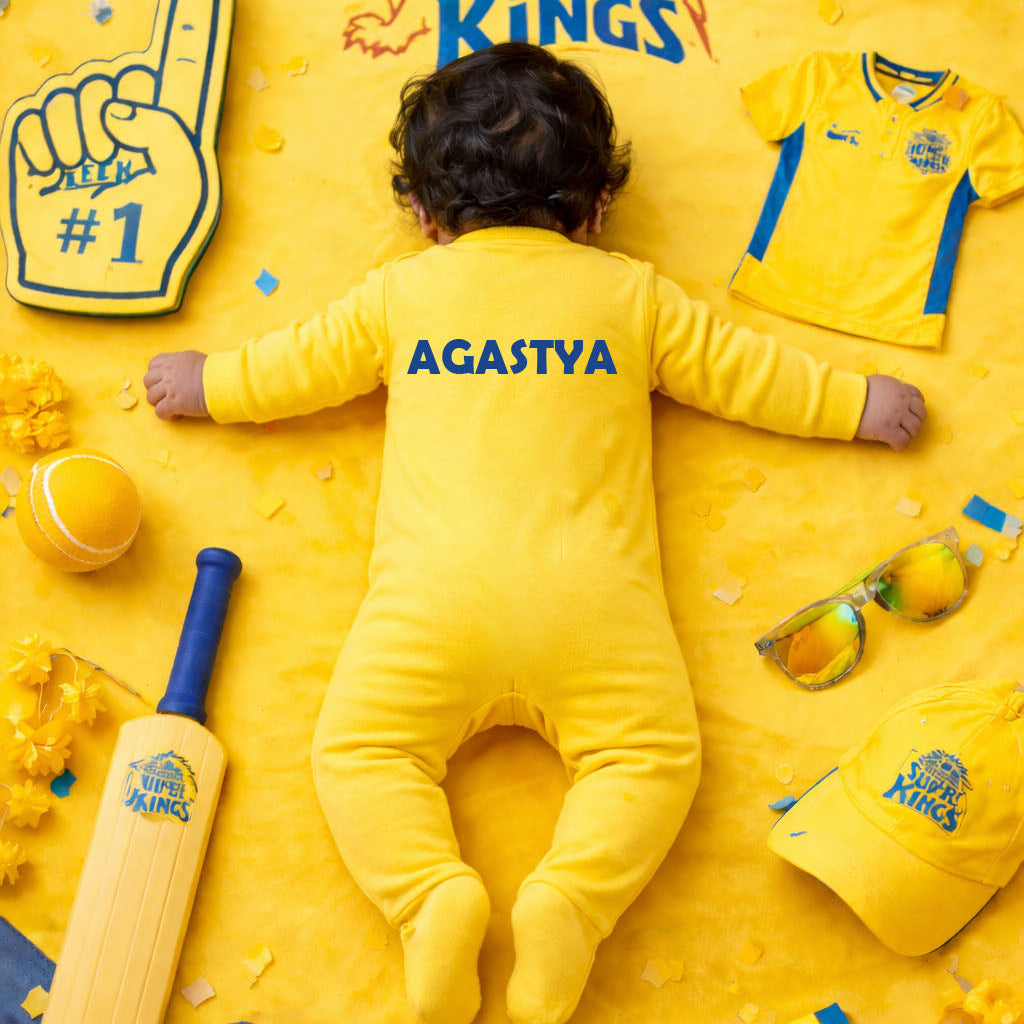 Baby in a yellow outfit with 'Chennai Super Kings' branding surrounded by sports-themed items on a yellow background.