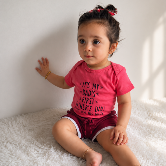 Child wearing a pink shirt with text sitting on a white surface
